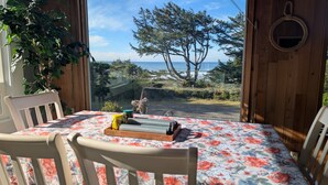 Un comedor con una mesa dispuesta para dos, con vistas a un paisaje escénico de árboles y el mar.