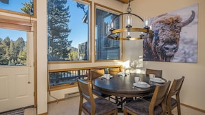 A dining area with a round table, chairs, and a chandelier. - Beautiful home w/fireplace, amazing views & community hot tub - Hidden Village Cozy Getaway (Gallatin Gateway)
