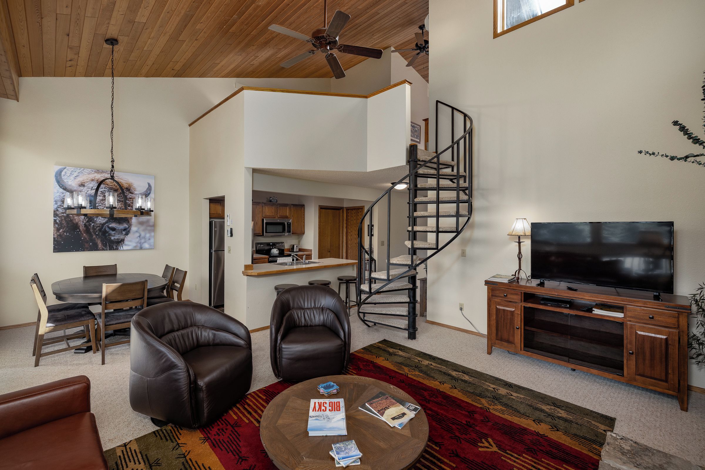 A modern living room with a spiral staircase, a dining area, and a kitchen.