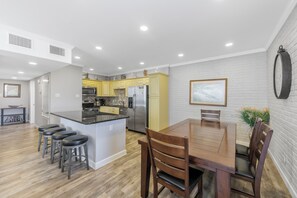 Una cocina moderna con una isla central, una mesa de comedor de madera y taburetes de bar.