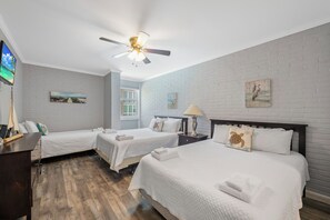 Habitación de hotel con dos camas, ventilador de techo y obras de arte en las paredes.