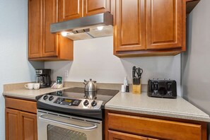 Une cuisine avec des meubles en bois, une cuisinière en acier inoxydable, une machine à café et un grille-pain.