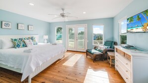 A bedroom with a bed, a desk, a chair, and a view of the beach through a door. - Tropical home has 3 comfortable bedrooms and 3 full baths. Screened in porch! Ch (Port Aransas)