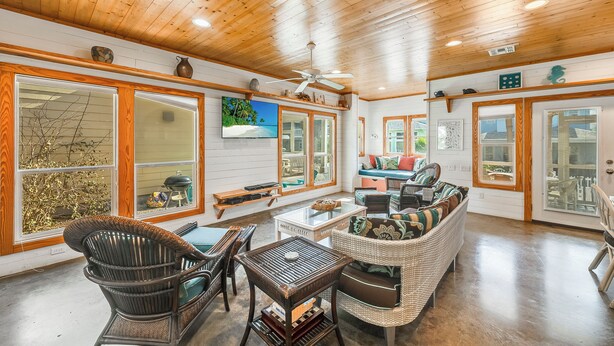 A spacious living area with wicker furniture, large windows, and a ceiling fan. - Tropical home has 3 comfortable bedrooms and 3 full baths. Screened in porch! Ch (Port Aransas)
