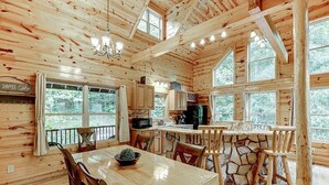 L’intérieur d’un chalet en bois comprend un coin repas, une cuisine et de grandes fenêtres.