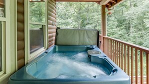 Un bain à remous sur une terrasse en bois, avec vue sur une forêt.