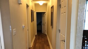 Un corridoio con pavimento in legno, pareti bianche e una lampada a soffitto.