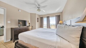 Ett hotellrum med en säng, en tv på en byrå, en takfläkt och utsikt över omgivningarna.