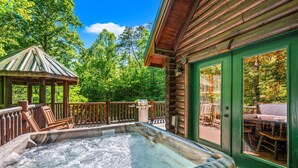 Un bain à remous sur une terrasse en bois, agrémentée d’un gazebo et de mobilier d’extérieur.