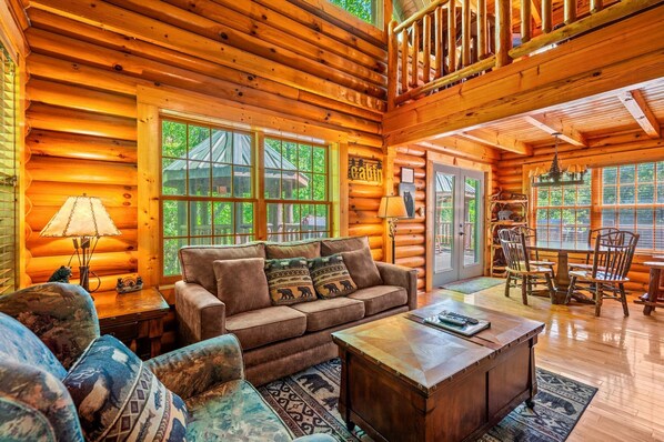 A log cabin interior with a sofa, coffee table, and dining area.