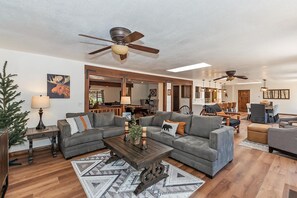 A spacious living room with a sectional sofa, a coffee table, and a ceiling fan.