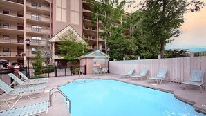 Una piscina con sillas de descanso, un edificio pequeño y una valla.