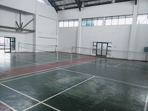 Enjoy a game of tennis on our indoor court, marked with white lines and featuring a green and red surface.