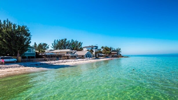 Una proprietà fronte spiaggia con acque cristalline, una spiaggia sabbiosa e diverse case.