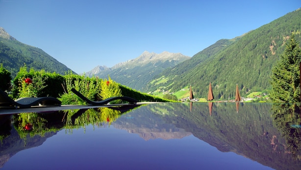 A serene lake with a clear reflection of the surrounding mountains and a bridge. - Lifestyle Panorama Hotel Erika (Neustift Im Stubaital)