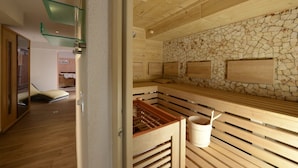 A sauna room with wooden benches, a stone wall, and a glass shelf. - Lifestyle Panorama Hotel Erika (Neustift Im Stubaital)