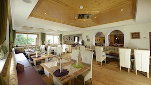 A spacious dining area with wooden tables and chairs, a long bench seating area, and large windows providing natural light. - Lifestyle Panorama Hotel Erika (Neustift Im Stubaital)