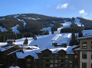 Ein schneebedeckter Berg mit einer Skipiste und Gebäuden am Fuße.