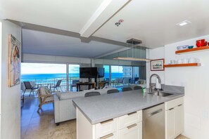 Eine moderne Küche mit einer großen Kochinsel, ein Essbereich mit Aussicht und ein Balkon mit Pool.