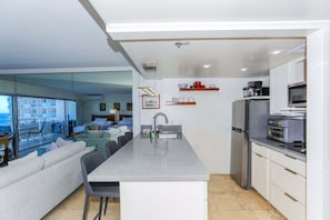 Eine moderne Küche mit einer zentralen Kochinsel, Edelstahlgeräten und Blick auf einen Balkon.