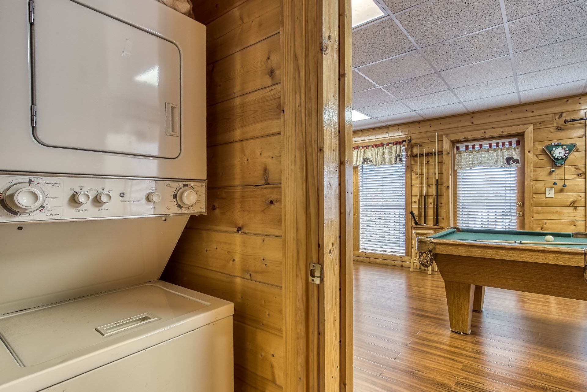 Un intérieur en bois avec une table de billard, un lave-linge et une horloge murale.