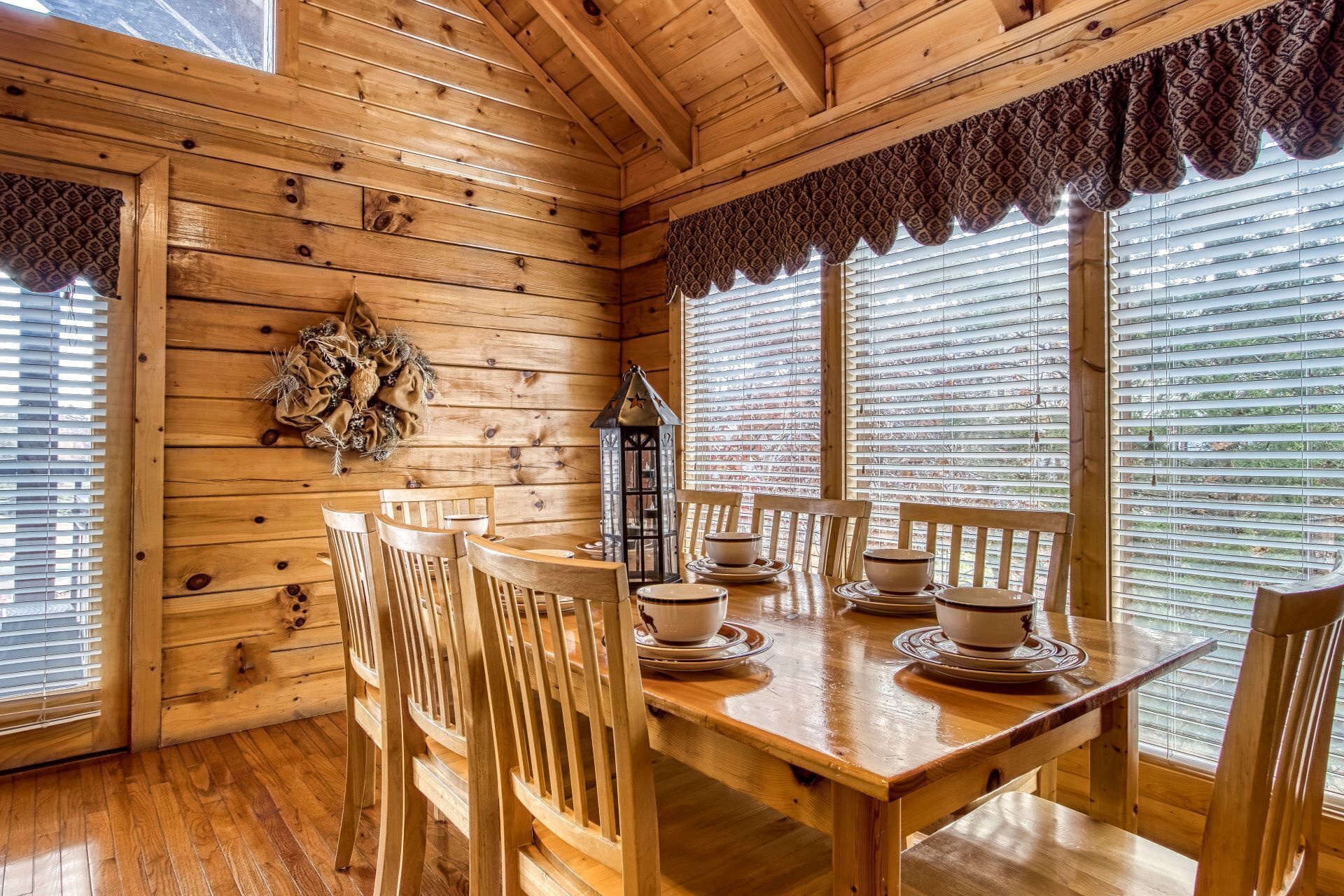 A wooden interior with a dining table set for four, surrounded by chairs.