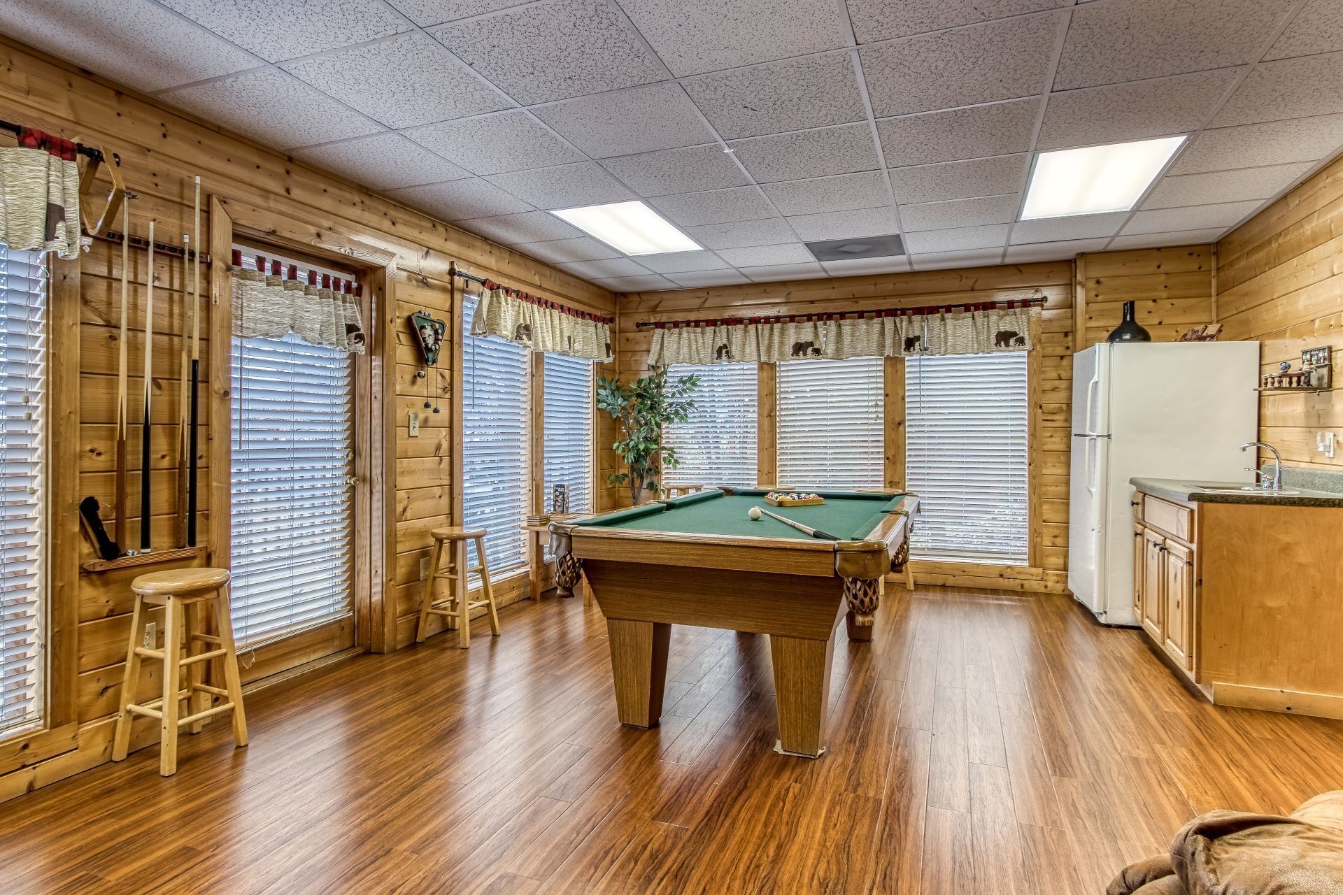 Un intérieur en bois comprenant une table de billard, un réfrigérateur et un coin cuisine.