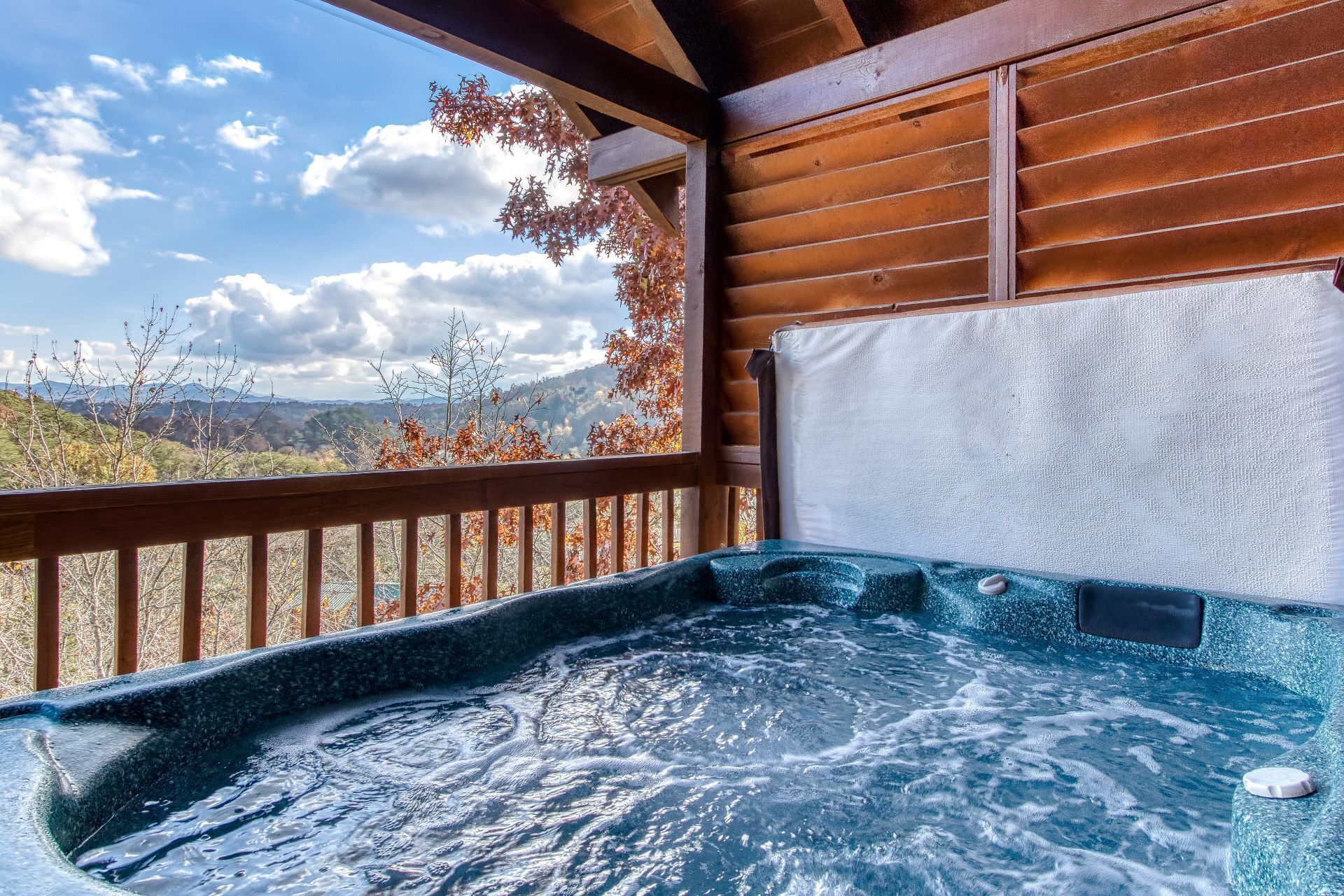 A hot tub with a wooden deck and a view of mountains.