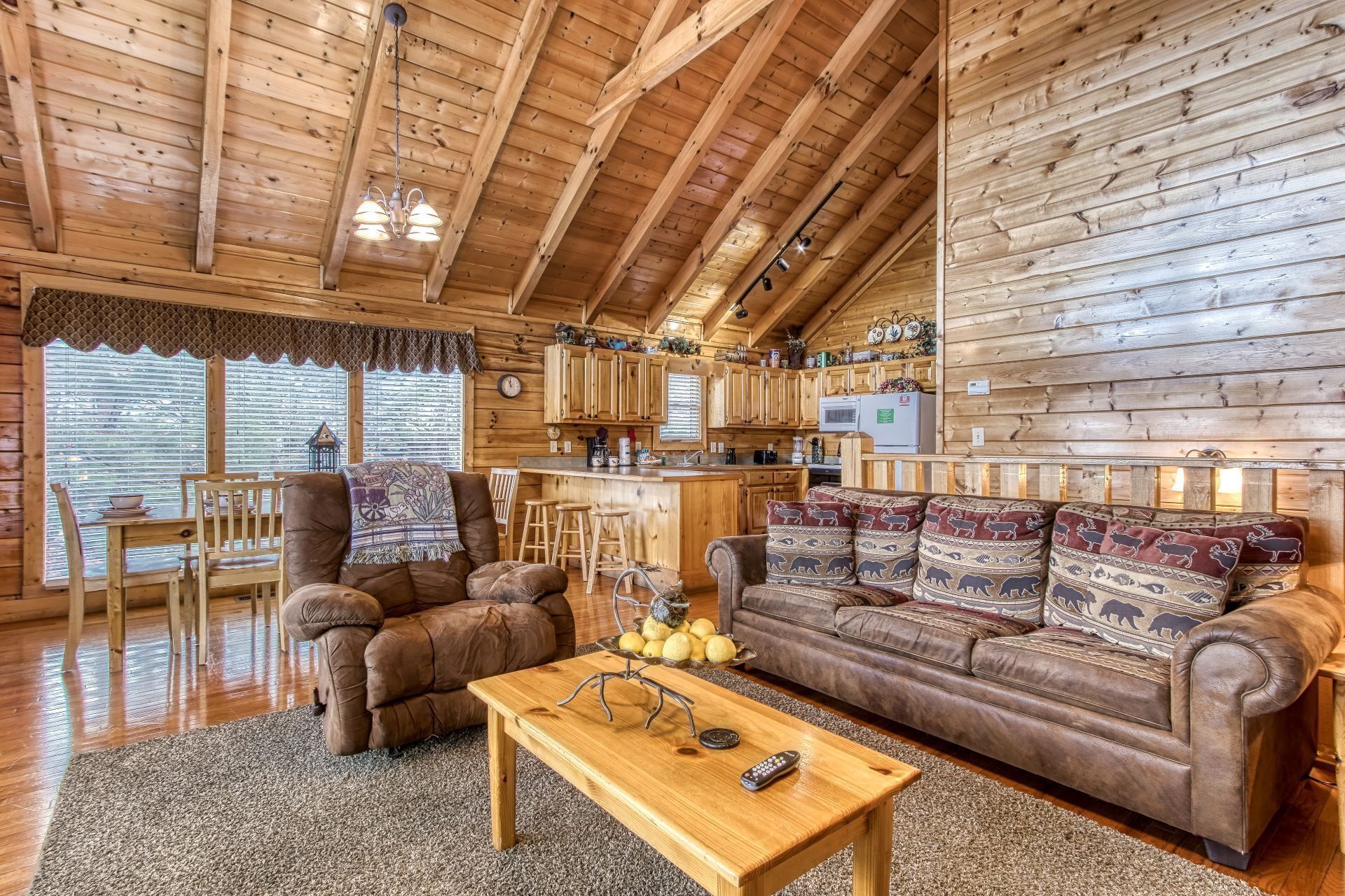A cozy log cabin interior with a living room, kitchen, and dining area.