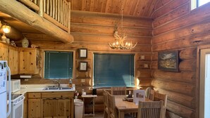 A log cabin interior with a kitchen, dining area, and a cozy seating area. - Hurd Cozy Log  Cabin (Greer)