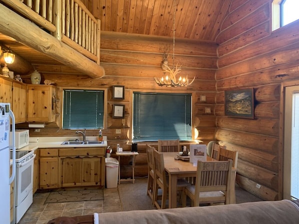 A log cabin interior with a kitchen, dining area, and a cozy seating area. - Hurd Cozy Log Cabin (Greer)