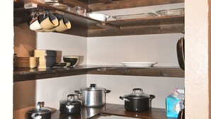 A kitchen with wooden shelves, a tiled floor, and a small countertop.