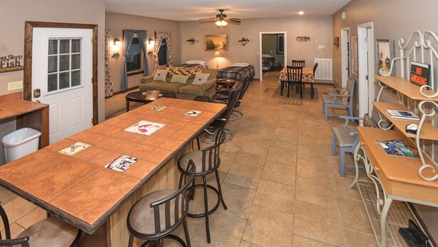 A spacious kitchen with a long wooden table, bar stools, and a dining area with chairs.