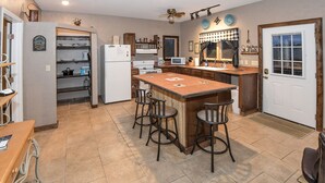 A kitchen with a central island, bar stools, a microwave, and a refrigerator.
