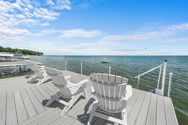 A wooden deck with white Adirondack chairs and a boat wheelhouse.