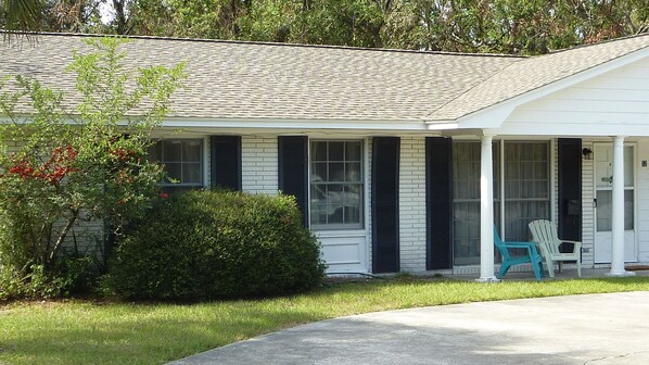 A single-story house with a covered porch, a small garden, and a mailbox.