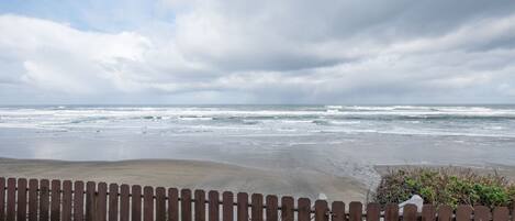 A beach view with a wooden fence in the foreground.