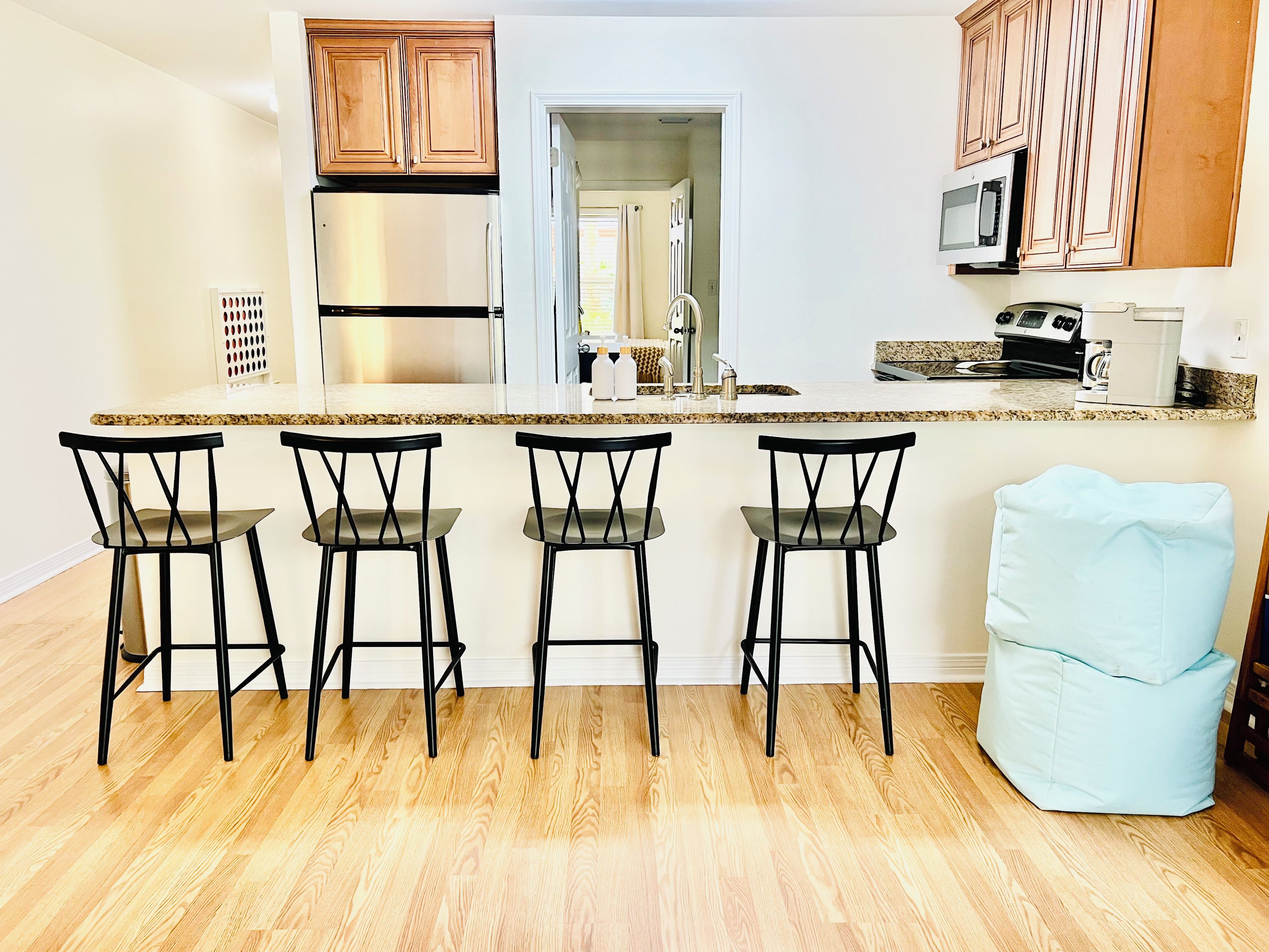 A kitchen with a central island, bar stools, a microwave, and wooden cabinets.