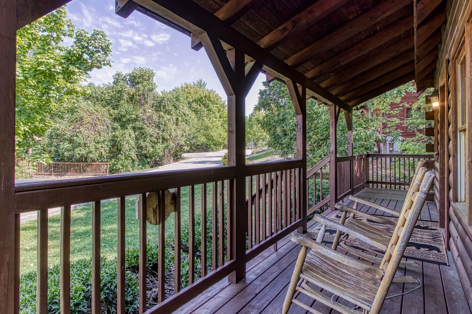 A wooden porch with a view of a road and trees.