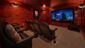 Um cinema acolhedor com paredes de madeira, uma tela grande e poltronas reclináveis confortáveis.