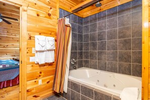Bagno di una cabina in legno con vasca, pareti piastrellate e rivestimenti in legno.