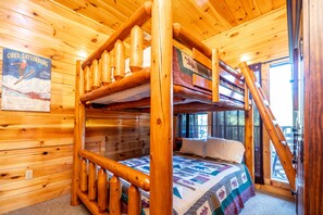 A wooden cabin with a bunk bed, a poster on the wall, and a window with a view.