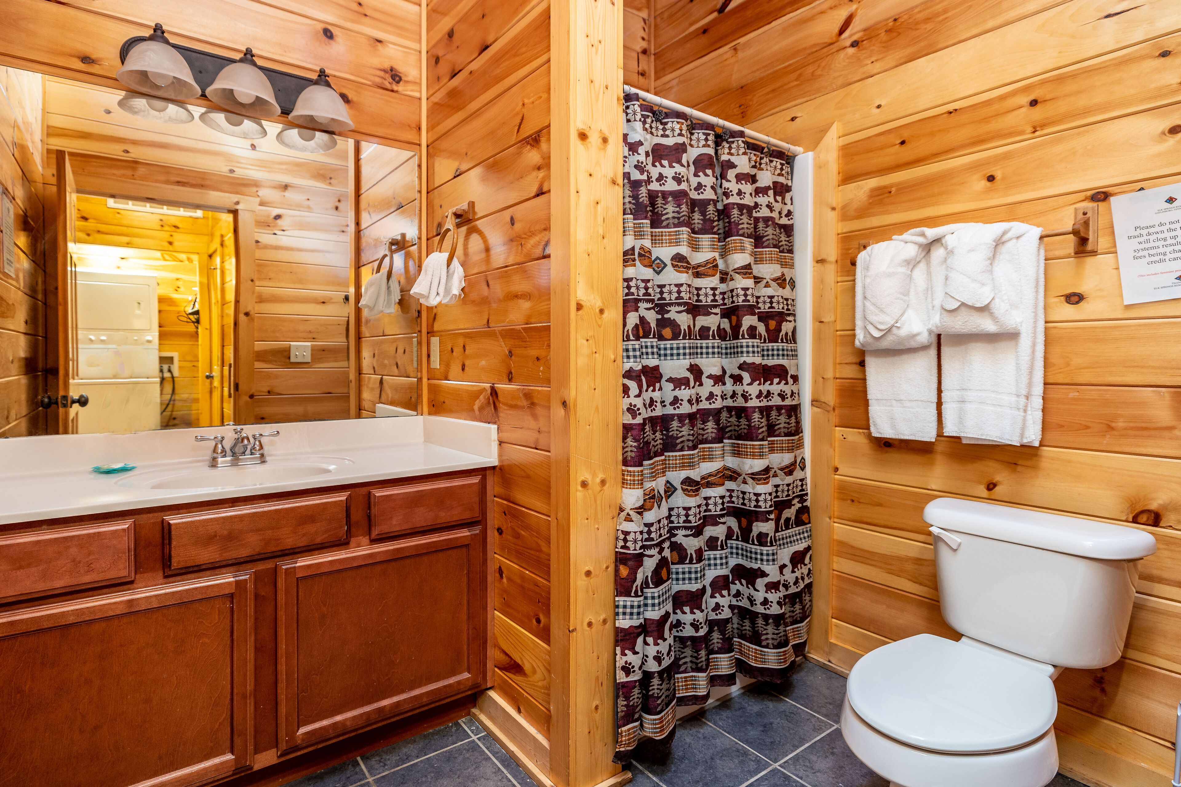 A wooden bathroom with a sink, mirror, and toilet.