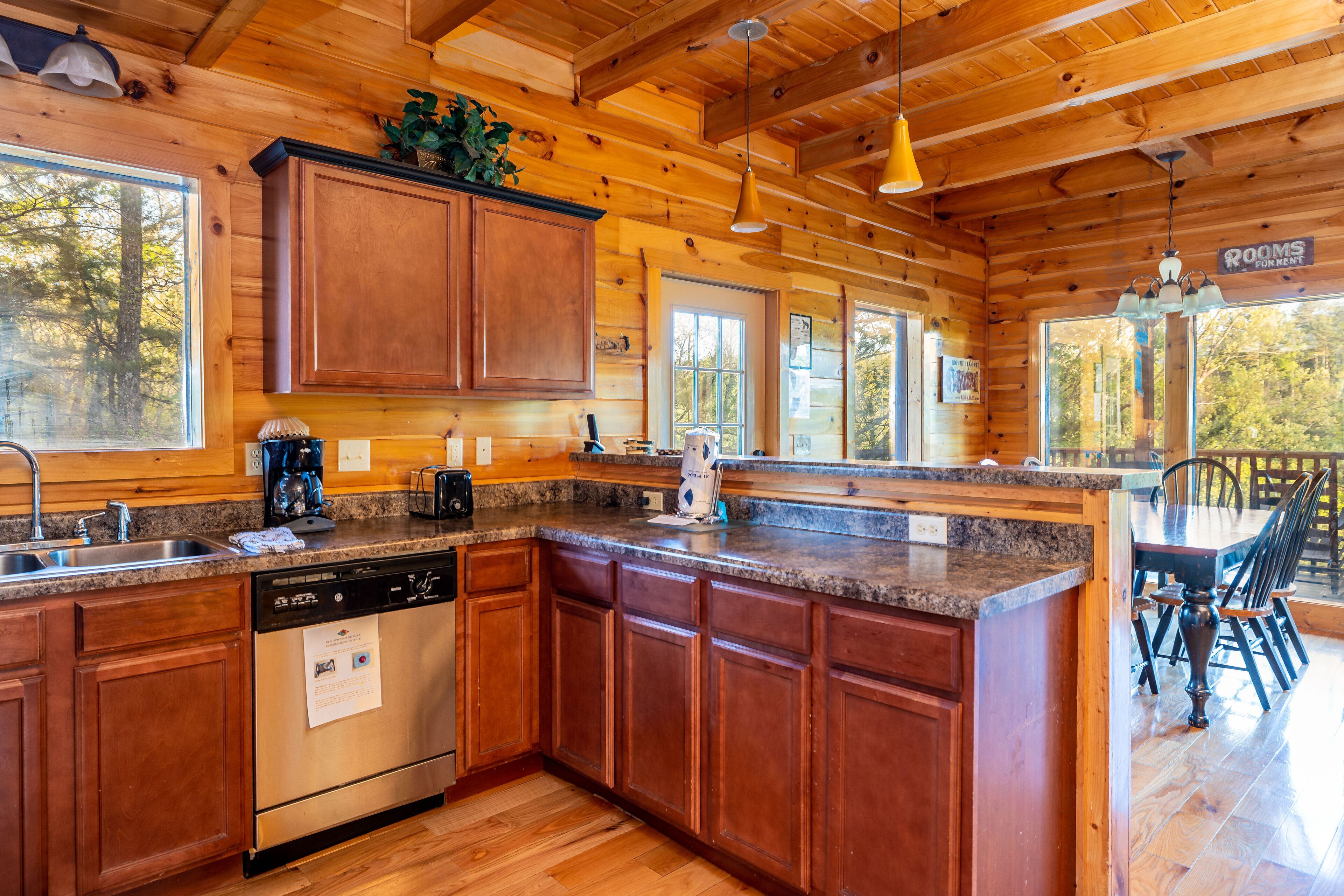 A wooden cabin-style kitchen with granite countertops, wooden cabinets, and a built-in dishwasher.