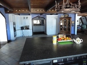 Una cucina con un'isola grande, mobili bianchi e un lampadario.