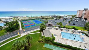 Ein Resort mit Pool, Tennisplätzen und Blick auf den Strand.