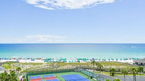 Blick auf einen Strand mit einem Tennisplatz und einer Promenade.