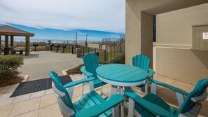 An outdoor patio with a round table and matching chairs, a covered seating area, and a view of the beach. - GROUND FLOOR PREMIUM! Phoenix III ~ Corner Condo on the BEACH! (Orange Beach)