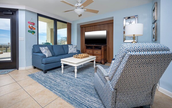 A living room with a blue sofa, a white coffee table, and a patterned armchair. - GROUND FLOOR PREMIUM! Phoenix III ~ Corner Condo on the BEACH! (Orange Beach)