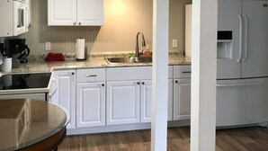 A compact kitchen with white cabinets, a sink, and a refrigerator.